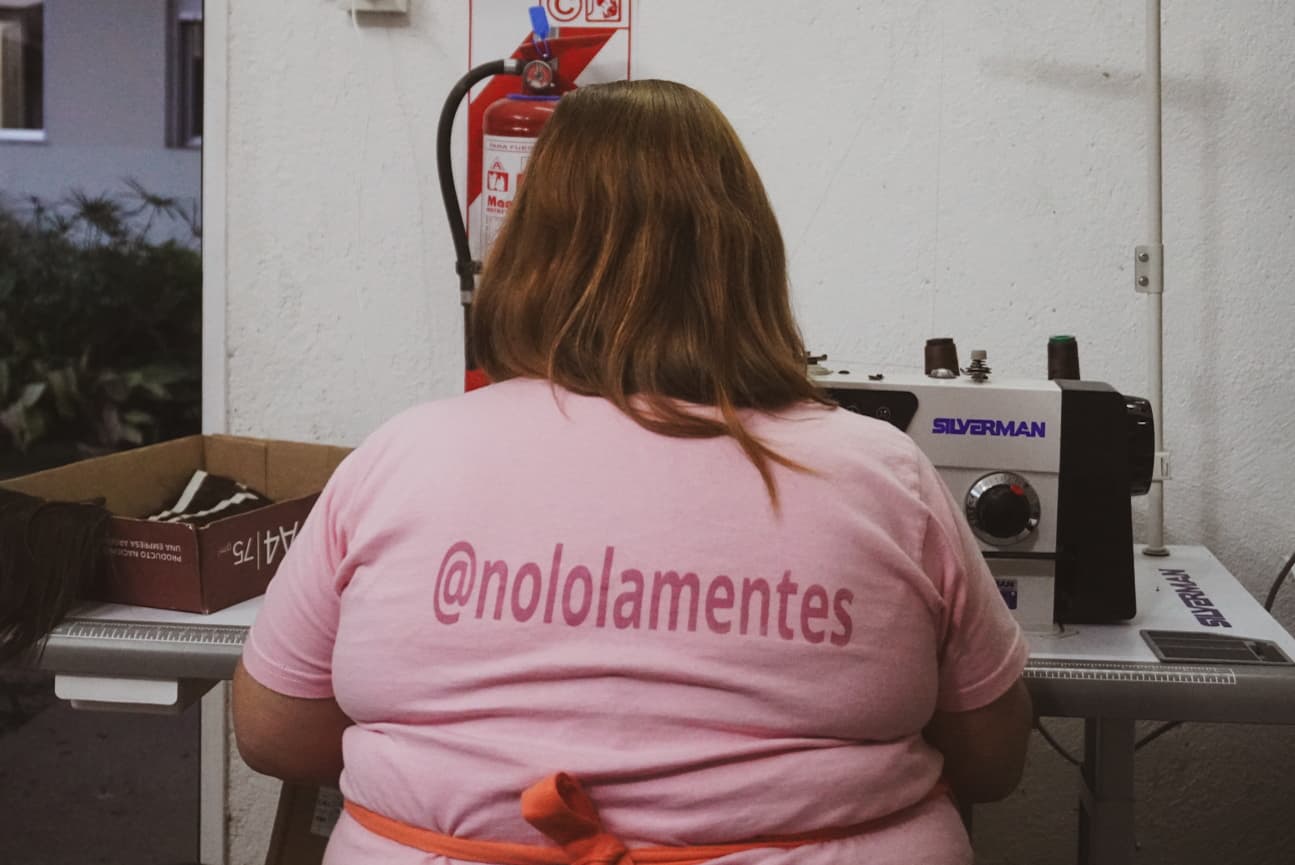 Voluntaria de noLOLAmentes confeccionando una peluca en la máquina de coser del taller